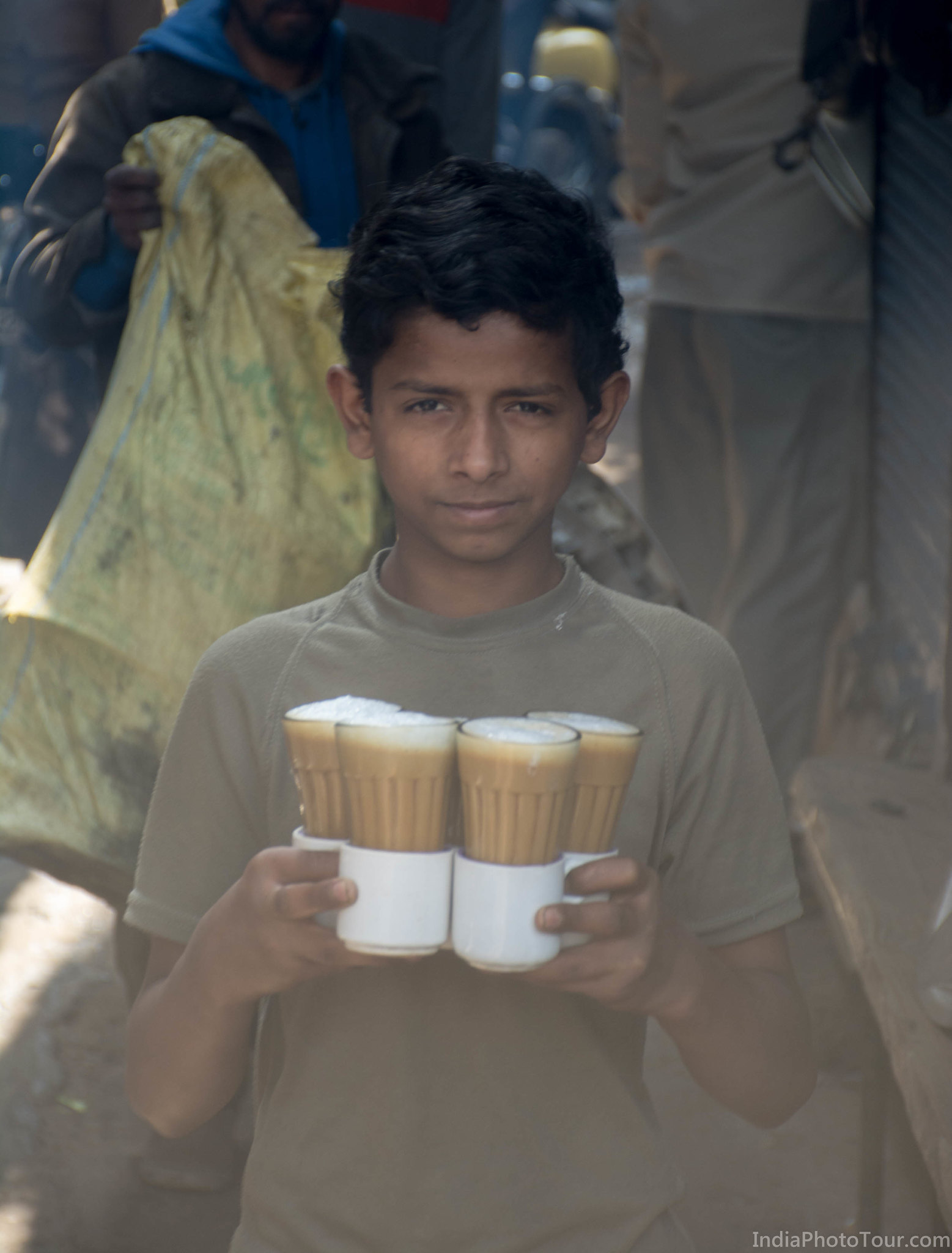 A boy in the street carrying tea
