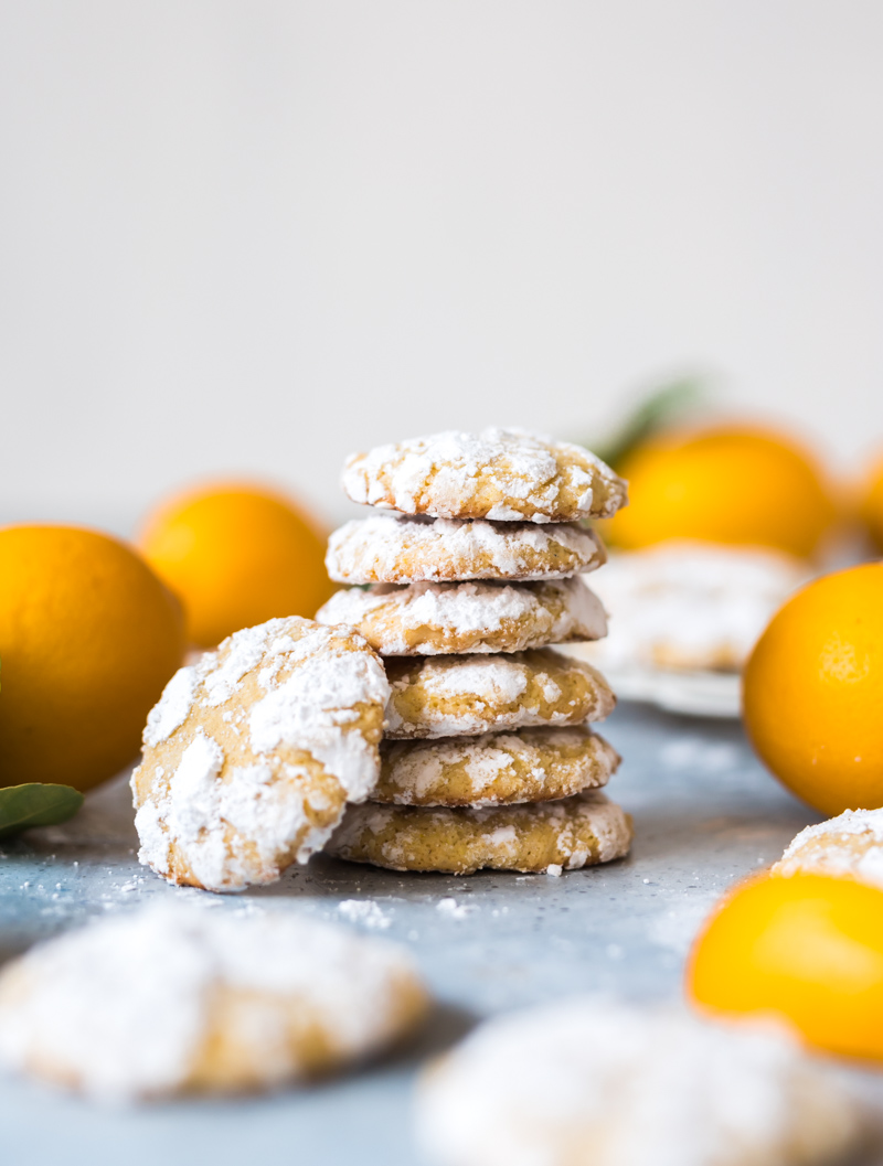 Ginger Cardamom Meyer Lemon Crinkle Cookies in a stack with whole meyer lemons