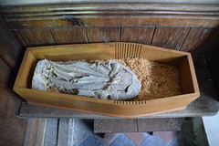 headless statue in a child's coffin