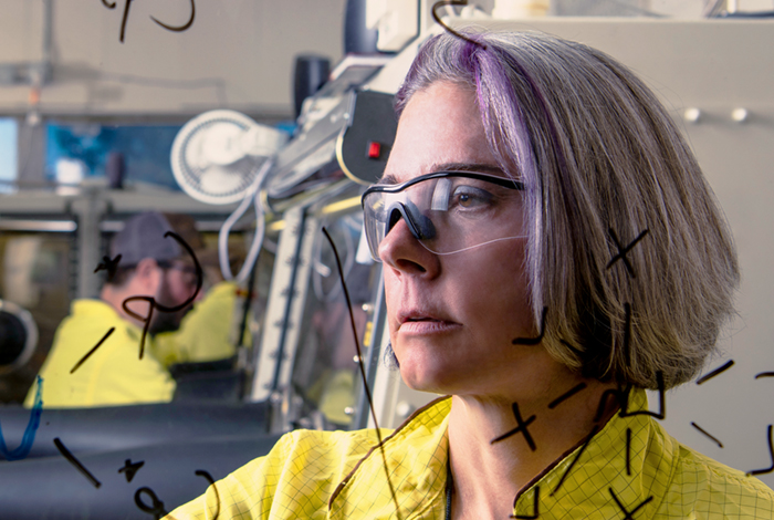 A woman wearing safety glasses standing in a lab.