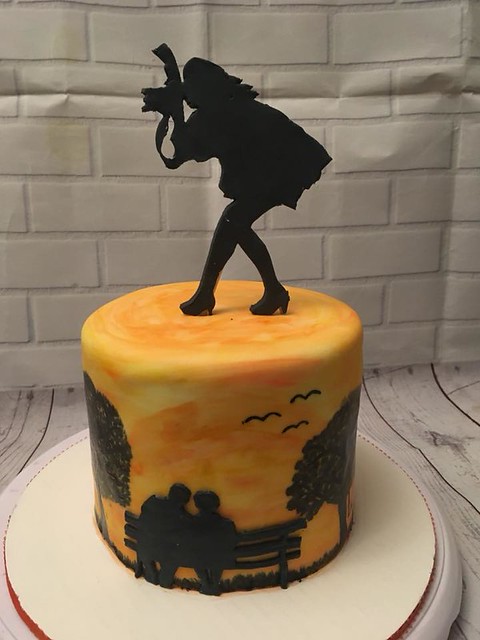 PurpleDaisy Cakes. Fondant, painted on sunset, trees, grass, birds. People and bench, and photographer are fondant silhouettes. By Alicia Mason