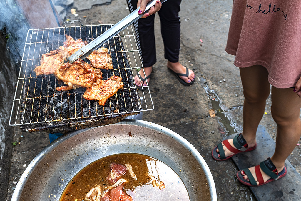 Girl grilling pork chops in District 6 alley--Saigon