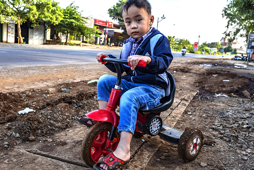 Boy riding a tricycle on side of road--Ea Kly