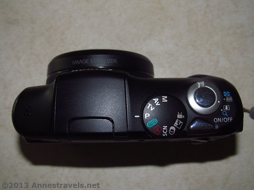 Top view of the Canon PowerShot SX150 IS.  Note the Mode wheel, On/Off button, Zoom trigger (around the shutter button), and shutter button (counter-clockwise from left).