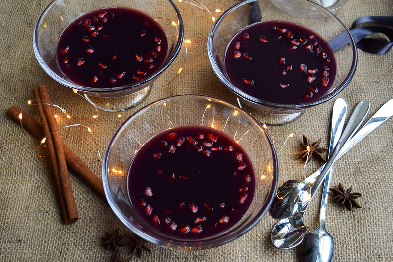 Mulled Wine Jellies in glass dishes studded with pomegranate seeds with dessert spoons.