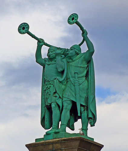 Verdigris copper statue of two ancient Vikings playing a horn instrument called a Lur in Copenhagen, Denmark