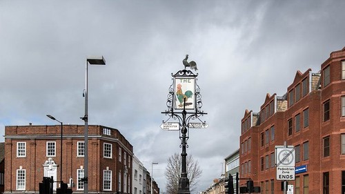 The Cock, which dates to around 1907, is a tall structure which was originally a grand gas lamp-post and pub sign, later converted to electricity and then to a road sign with multiple finger posts