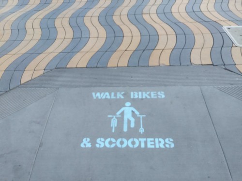 Walk Bikes and Scooters message painted on sidewalk intersections in Santa Monica