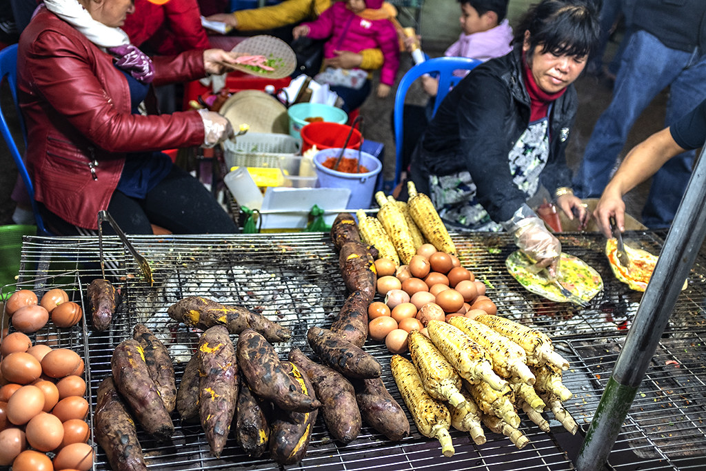 Woman selling grilled corn, yams and eggs near the central market--Da Lat