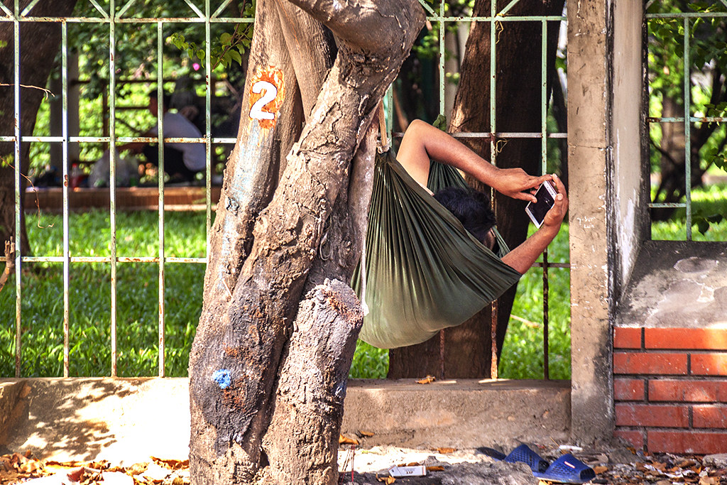 Man on hammock looking at smart phone--Saigon