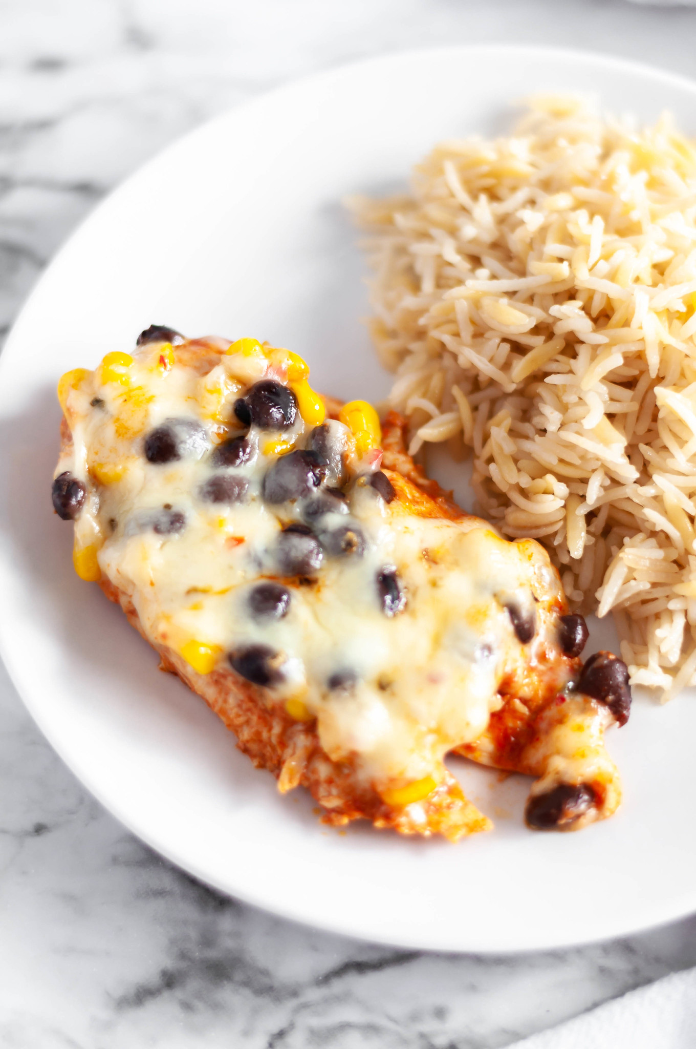 Baked Enchilada Chicken is a great addition to your 30 minute meal collection. Chicken breasts covered in enchilada sauce, corn, black beans and cheese makes a simple and healthy weeknight meal.