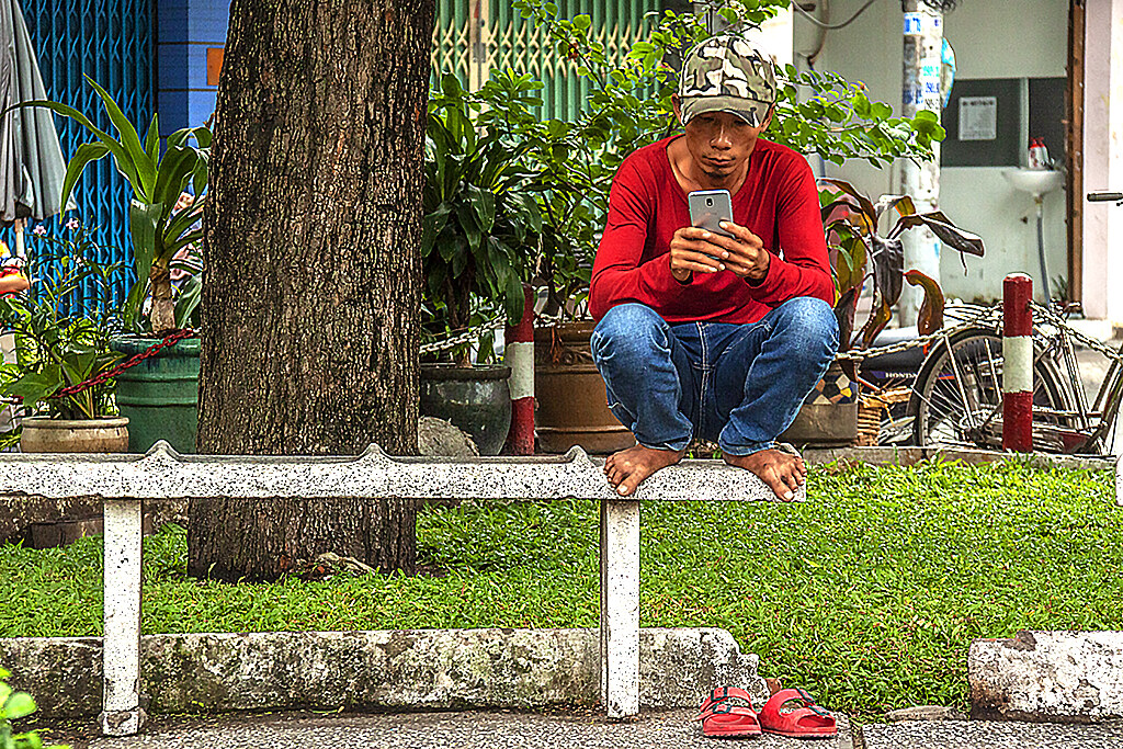 Man squatting on park bench in District 6--Saigon